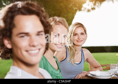 Italie, Toscane, Magliano, jeune homme et femmes à manger table, smiling, portrait Banque D'Images