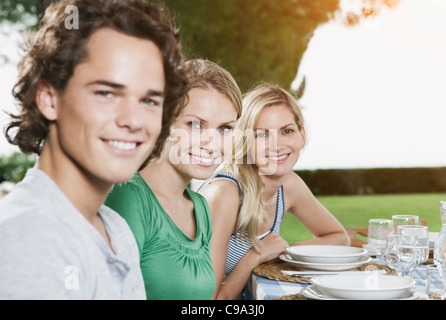 Italie, Toscane, Magliano, jeune homme et femmes à manger table, smiling, portrait Banque D'Images