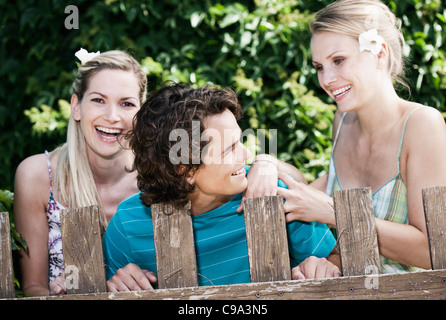 Italie, Toscane, Magliano, jeune homme et femmes debout derrière clôture en bois, smiling Banque D'Images