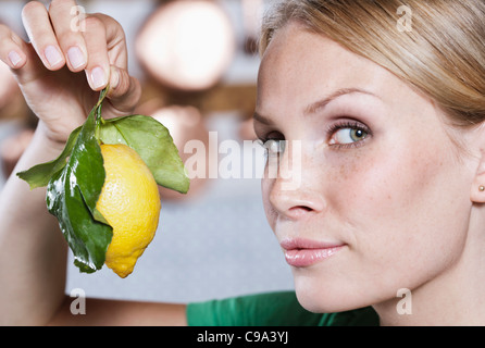 Italie, Toscane, Magliano, Close up of young woman holding citron, portrait Banque D'Images