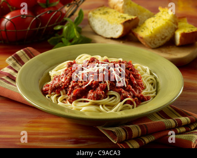 Spaghetti avec sauce à la viande garnie de fromage Parmesan et servi avec du pain à l'ail Banque D'Images