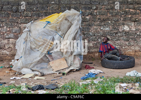 Un garçon de la rue se trouve à l'extérieur la maison de l'un des chefs de bande de base Mbaraki, dans le centre de Mombasa, au Kenya. Banque D'Images
