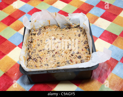 Faire un gâteau de Noël, le gâteau terminé prêt pour la cuisson dans un carré bordé d'étain de cuisson de papier sulfurisé Banque D'Images