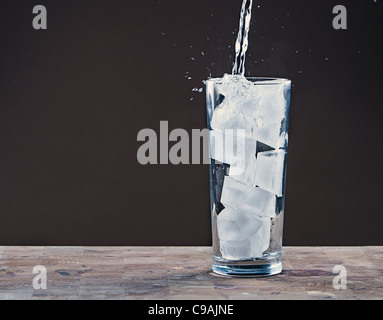 Verser de l'eau dans un verre rempli de cubes de glace Banque D'Images