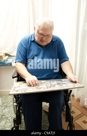 Personnes âgées handicapées homme en fauteuil roulant faire un puzzle denteux pour garder son esprit actif Banque D'Images