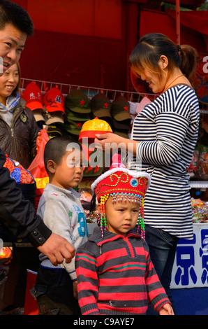 Famille chinoise en vacances sur la semaine nationale de l'achat de chapeaux pour leurs deux garçons dans Forbidden City Beijing Chine Banque D'Images