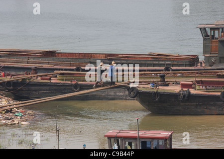 Deux hommes à l'aide d'un pôle à l'étui pour charger junk sur une barge à Shijiazhuang, Chine Banque D'Images