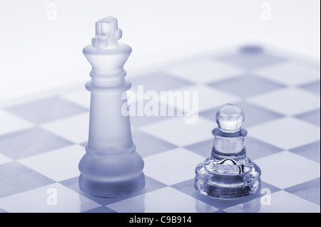 D'échecs en verre. Un pion et un roi. Dans les tons bleu. Il est isolé sur un fond blanc. Banque D'Images