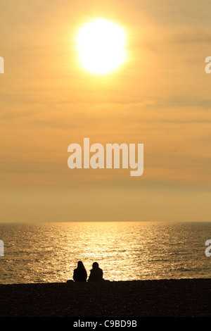 La silhouette du couple sur la plage de Brighton en regardant le coucher du soleil en automne inférieur Banque D'Images