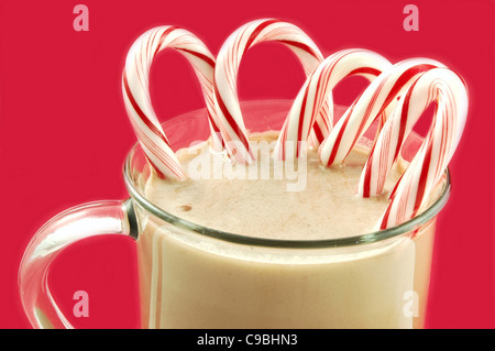 Mug de Noël chaud cacao avec des cannes de bonbon sucré isolé sur fond rouge Banque D'Images