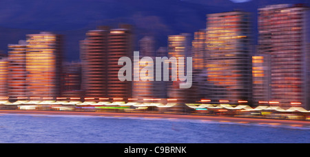 Profil de l'architecture floue la plage Levante de Benidorm au coucher du soleil, avec le soleil qui reflète sur windows et les bâtiments. Banque D'Images