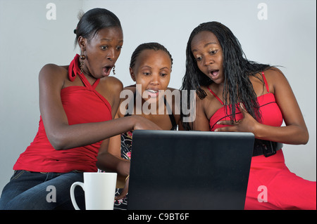 Les jeunes femmes kenyanes réunis autour d'un ordinateur portable, Nairobi, Kenya Banque D'Images