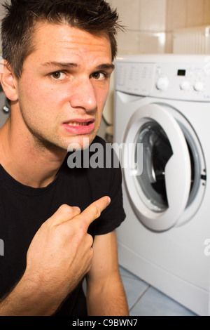 Jeune homme malheureux avec lave linge Banque D'Images