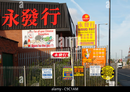 Un tableau de signes, certains en chinois, sur un mur et des clôtures. , Beswick, Manchester, Angleterre, RU Banque D'Images