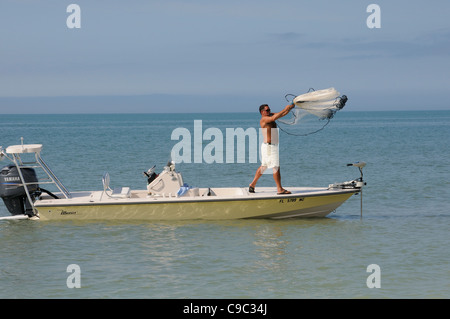 L'homme de jeter un filet de pêche d'un petit bateau sur la côte du golfe du Mexique, la Floride Etats-unis pour appât Pêche Banque D'Images