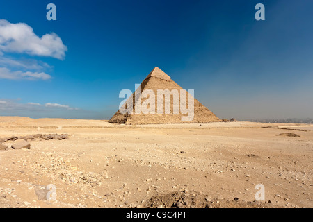 La pyramide de Khafré assise seule dans les sables du désert au site des pyramides de Gizeh avec le Caire le smog visible sur la droite. Banque D'Images