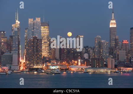 La pleine lune se lève au-dessus de l'horizon de Manhattan au crépuscule comme vu sur le fleuve Hudson, du New Jersey Banque D'Images