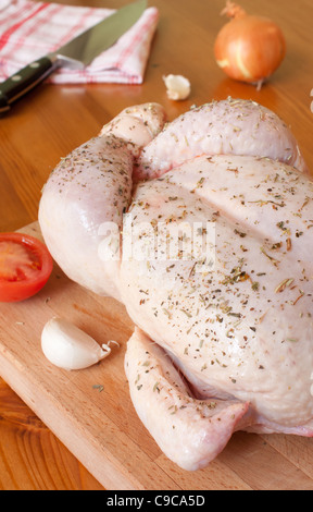 Préparation d'un poulet, avec des herbes aromatiques, ail, oignons et tomates Banque D'Images
