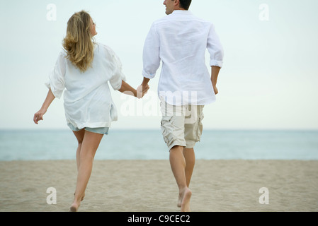 Couple marche main dans la main sur la plage, vue arrière Banque D'Images