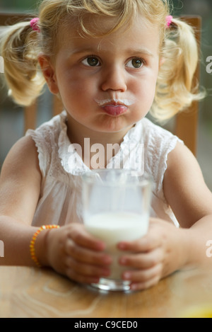 Petite fille avec une moustache de lait bénéficiant d''un verre de lait Banque D'Images