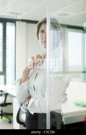 Businesswoman standing derrière cloison de verre in office Banque D'Images