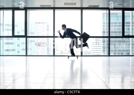 Businessman skateboarding avec cuvette et serviette à mains Banque D'Images