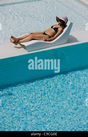 Jeune femme portant chapeau de soleil sur un transat au bord de la chaise longue Banque D'Images