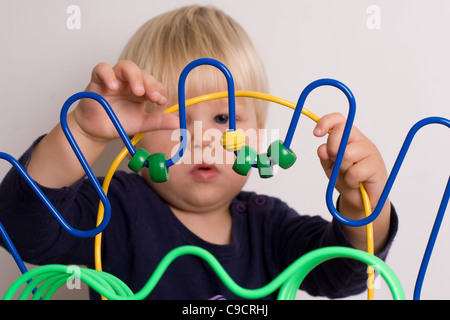 Jeune garçon joue avec les perles de couleur sur une table de jeu Banque D'Images