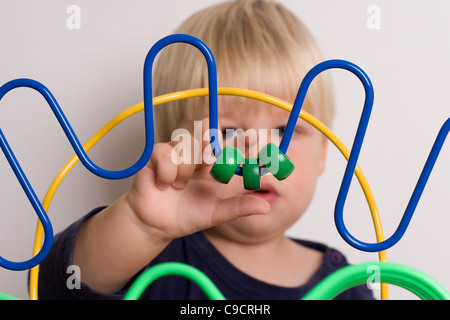 Jeune garçon joue avec les perles de couleur sur une table de jeu Banque D'Images