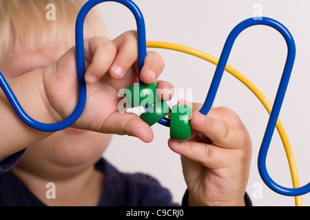 Jeune garçon joue avec les perles de couleur sur une table de jeu Banque D'Images