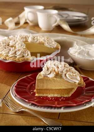 Toute une tarte à la crème de potiron avec une coupe garnie de crème fouettée Banque D'Images