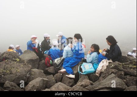 Les enfants de l'école japonaise pique-nique sur le sommet du mont Tateshina brumeux, Nagano, Japon. Banque D'Images