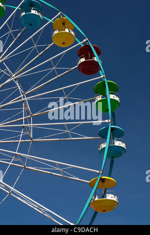 Les voitures avec des auvents colorés sur une grande roue de foire ride. Banque D'Images