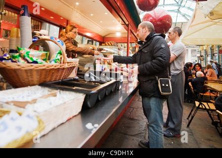 Londres Covent Garden Market hommes clients masculins étant servi par girl au comptoir de cafe snack-bar sous les décorations de Noël boules rouges géantes Banque D'Images