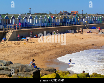 Front de Southwold en été avec des vagues se briser sur la plage et les cabanes de plage derrière Suffolk Angleterre UK Banque D'Images