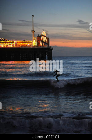 Les surfeurs peuvent profiter du magnifique coucher de soleil en attrapent quelques vagues près de la jetée du Palace Pier, sur le front de mer de Brighton au Royaume-Uni Banque D'Images