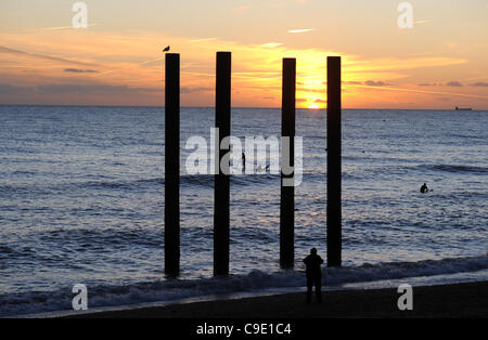 Les surfeurs peuvent profiter du magnifique coucher de soleil en attrapent quelques vagues près de la jetée du Palace Pier sur le front de mer de Brighton après une autre après-midi glorieuse de temps chaud et ensoleillé. Banque D'Images