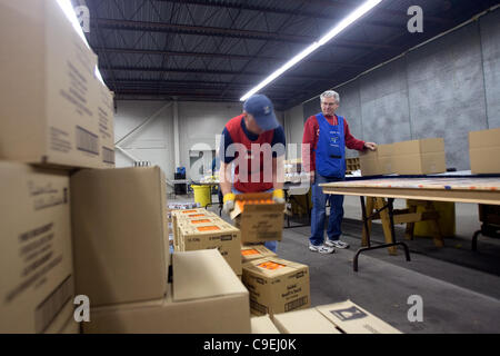 London, Ontario, Canada - le 8 décembre 2011. Jean Perrin, gauche déplace une boîte d'aliments emballés de façon Bert Cowan peut emballer dans des paniers de nourriture à l'Armée du Salut 2011 toy et centre de distribution de nourriture à l'intérieur de la construction au Western Fair District. Cette année, l'Armée du Salut s'attend à p Banque D'Images