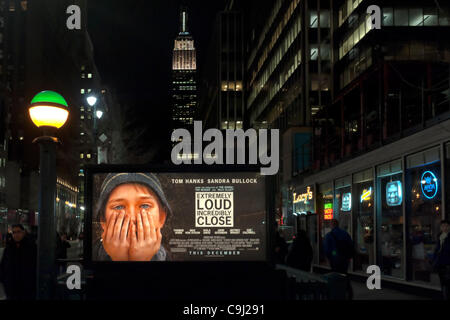 Manhattan, New York, USA - 9 janvier 2012 : l'affiche du film "extrêmement fort et incroyablement près' est allumé sur Penn Station métro vendredi soir avec l'Empire State Building derrière elle. Le film de fiction est défini au moment de l'attaque terroriste de New York le 11 septembre 2001 sur les tours jumelles. Banque D'Images