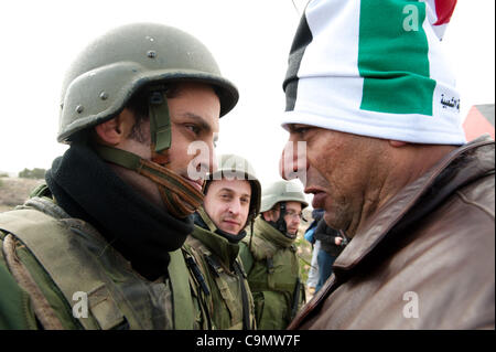 Territoires palestiniens occupés Al-Masara, vendredi 27 janvier. Un Palestinien portant un drapeau palestinien hat affronte des soldats israéliens dans une protestation contre la barrière de séparation israélienne en Cisjordanie vers le bas d'Al-Masara. Banque D'Images