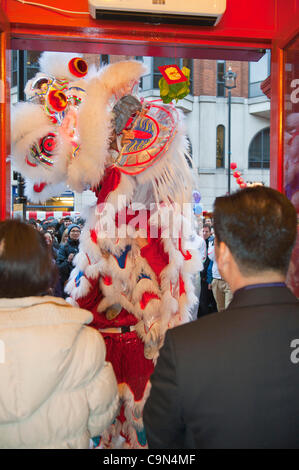 29 janvier 2012. Londres, Royaume-Uni - Un lion dancer la coutume traditionnelle de Cai Ching, littéralement plumer les verts, dans un magasin situé dans le quartier chinois -Le 10e anniversaire de célébrations du Nouvel An chinois à Trafalgar Square, sont les plus grandes célébrations à l'extérieur de la Chine. Photo:Graham Lawrence/Alamy News. Banque D'Images