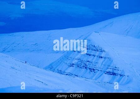 4e Février, 2012. Un grimpeur solitaire fait son chemin jusqu'à la sommet couvert de neige de Pen-y-Fan dans les Brecon Beacons au Pays de Galles ce soir alors que la nuit commence à tomber. Banque D'Images