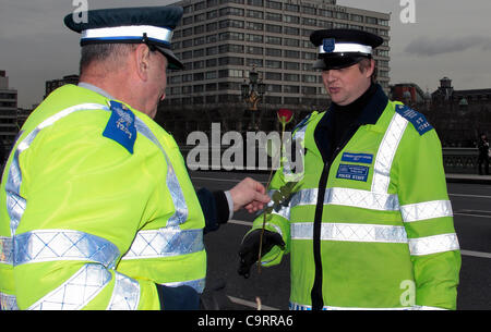 Deux agents de soutien communautaire de la police sur le pont de Westminster au cours de la République Roses pour protester contre des Martyrs, un officier a remis son collègue une rose rouge Banque D'Images