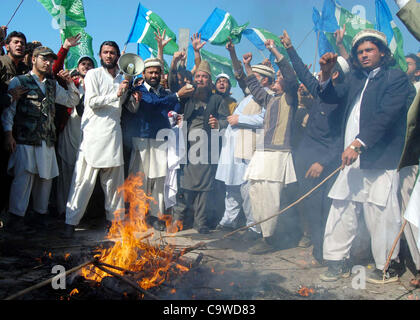 Les partisans du Jamat-e-Islami (JI) recueillir près de brûler bois comme ils protestent contre l'OTAN à Peshawar le vendredi 24 février 2012. Banque D'Images