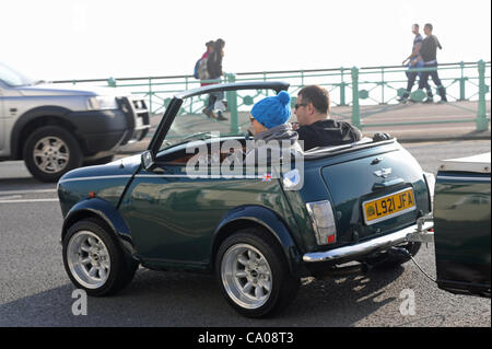 Brighton, UK. 12 mars, 2012. Un couple profiter du beau temps sur le front de mer de Brighton dans leur coupé Mini avec son toit. Crédit : Simon Dack/Alamy Live News Banque D'Images