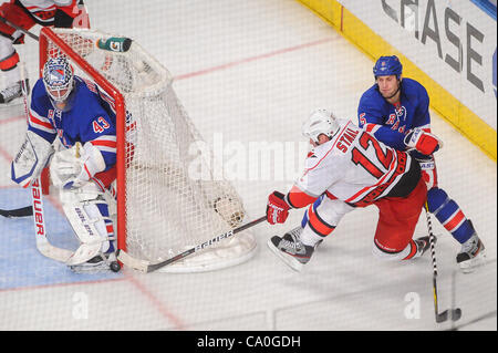 13 mars 2012 - Newark, New Jersey, États-Unis - Centre des Hurricanes de la Caroline Eric Staal (12) obtient un wraparound tourné sur les Rangers de New York le gardien Martin Biron (43) en dépit d'être vérifié pour la glace par le défenseur Dan Girardi (5) au cours de la troisième période d'action de la LNH entre les Hurricanes de la Caroline et le New York Ran Banque D'Images