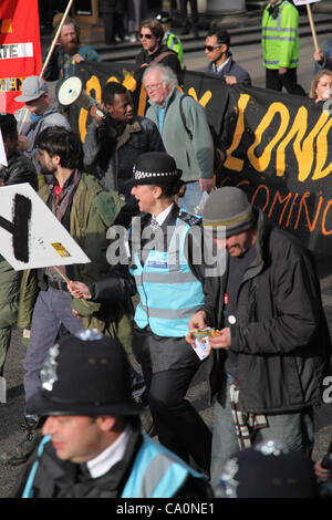 Londres, Royaume-Uni, le 14 mars, 2012 Un agent de liaison aux côtés de manifestants promenades holding a placard qui écrit le mot occupent. La police métropolitaine a déclaré que "l'Équipe de liaison de protestation ont été introduites afin d'améliorer le dialogue et la compréhension entre les manifestants et la police". Banque D'Images