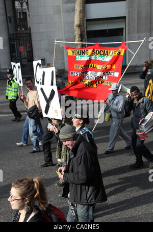 Londres, Royaume-Uni, le 14 mars, 2012 Un agent de liaison aux côtés de manifestants promenades holding a placard qui écrit le mot occupent. La police métropolitaine a déclaré que "l'Équipe de liaison de protestation ont été introduites afin d'améliorer le dialogue et la compréhension entre les manifestants et la police". Banque D'Images