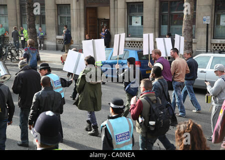 Londres, Royaume-Uni, le 14 mars, 2012 Un agent de liaison aux côtés de manifestants promenades holding a placard qui écrit le mot occupent. La police métropolitaine a déclaré que "l'Équipe de liaison de protestation ont été introduites afin d'améliorer le dialogue et la compréhension entre les manifestants et la police". Banque D'Images