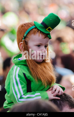 Belfast, Royaume-Uni. 17 mars, 2012. Jeune garçon sur les épaules des parents portant un chapeau vert et rouge/ginger beard sur St Patrick's Day Banque D'Images